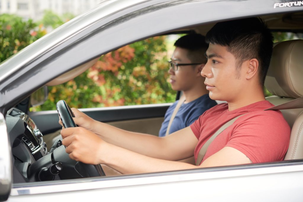 Profile view of confident young man wearing red T-shirt giving his best friend a lift, head and shoulders portrait